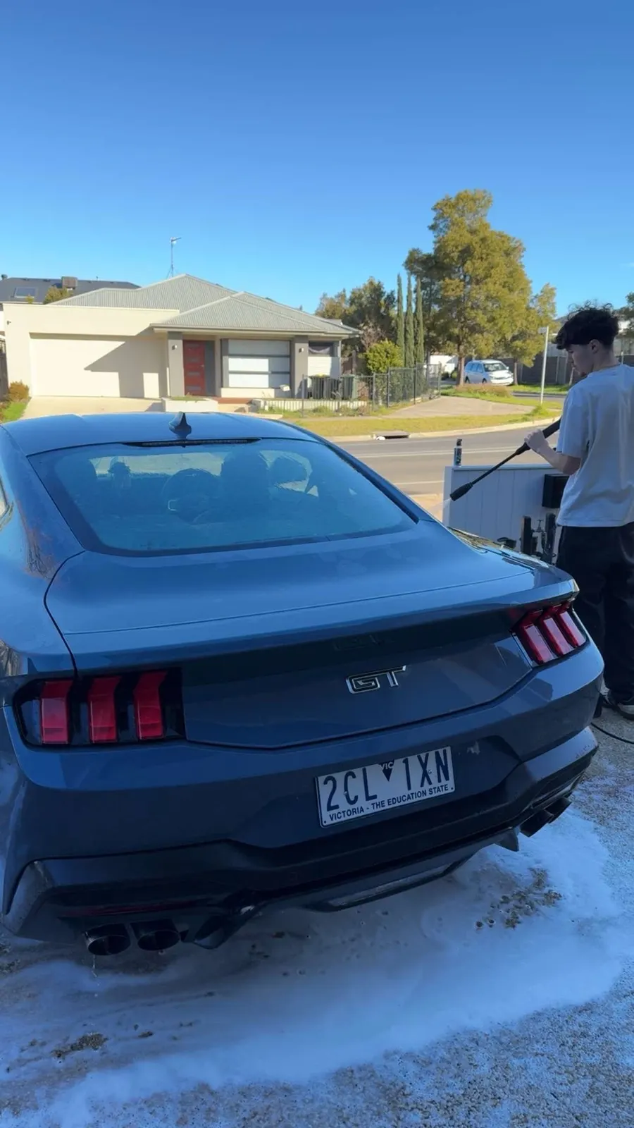 Dark blue Ford Mustang GT being pressure washed during a maintenance detail