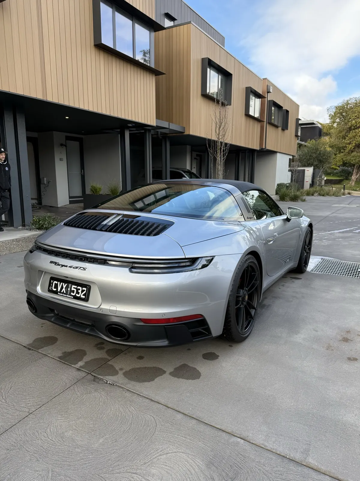 Silver Porsche 911 GTS freshly detailed, parked outside luxury residence